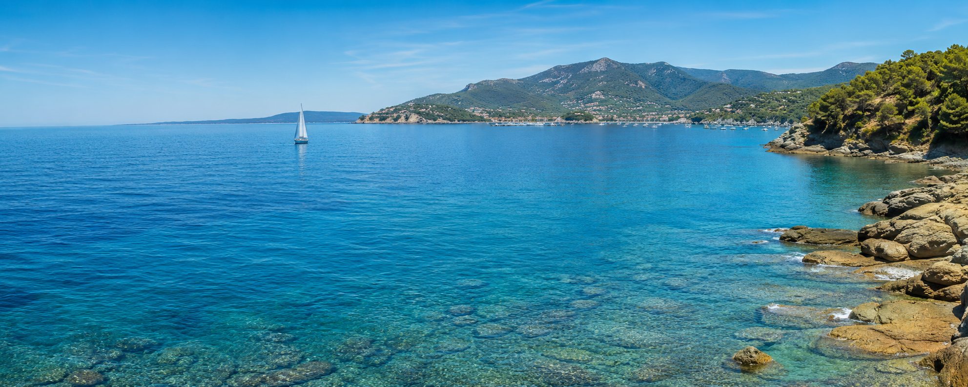 Baia dell'Elba con acqua cristallina e una barca a vela